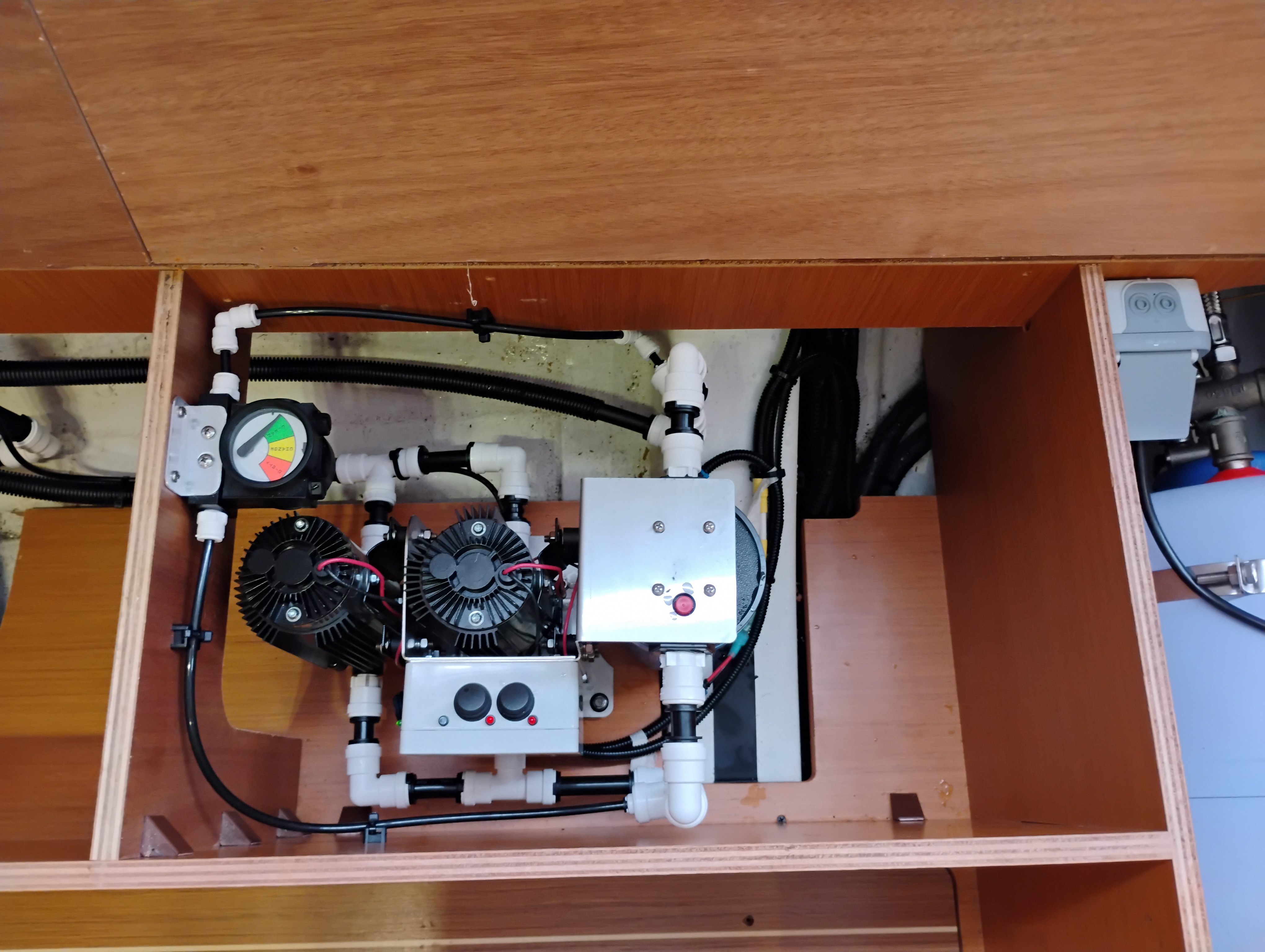 Watermaker product-water plumbing routed through a vessel freshwater tank manifold